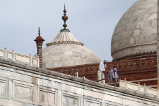 In this picture taken on May 30, 2020, workers stand on the railing of the Taj Mahal after it was damaged due to heavy rainstorm in Agra.