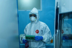 A laboratory staff members holds a spray bottle containing alcohol and a set of tubes filled with swab samples in the laboratory’s extraction room. Only laboratory staff and expert scientists are allowed to handle the samples. JP/Agung Parameswara