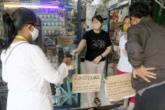 Safe distance: A shop owner serves customers outside her shop on Jl. Pamulang Raya in South Tangerang, Banten, on Monday.