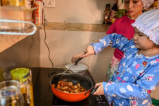 This photo taken on May 21, 2020 shows Moe Myint May Thu (right) and her mother Honey Cho cooking while filming a video at their house in Yangon. 