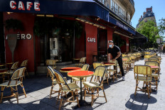 A staff member wearing face mask prepare the terrace of the Etienne Marcel cafe restaurant on May 31, 2020 in Paris, as France eases lockdown mesures taken to curb the spread of the COVID-19 pandemic.