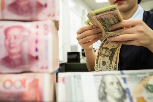 A Chinese bank employee counts 100-yuan notes and US dollar bills on Aug. 6, 2019, at a bank counter in Nantong in China's eastern Jiangsu province. 