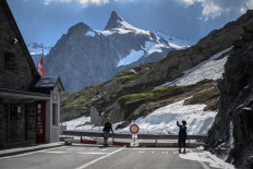 Tourists take a picture by a fence closing the Swiss-Italian border at Grand Saint Bernard pass on June 2, 2020, on the eve of Italy's unilateral reopening of its borders, amid the COVID-19 outbreak, caused by the novel coronavirus.Travellers to Switzerland from 29 countries will from July 6 have to register with the authorities and go into self-isolation to prevent a resurgence of the coronavirus, the government said on Thursday.