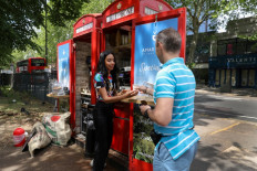Loreinis Mejia Hernandez from Colombia serves coffee to a customer at a converted telephone box she runs as a take-away coffee shop with her husband as the coronavirus disease (COVID-19) lockdown eases in Chiswick, West London, Britain, June 2, 2020. 
