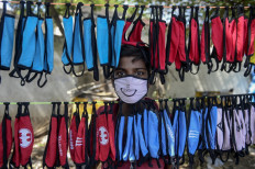 A street vendor poses as he arranges facemasks to sell on the roadside as a preventive measure against the spread of the COVID-19 coronavirus on the outskirts of Hyderabad on June 5, 2020. 