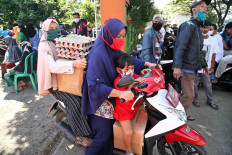 Two women and a child ride a motor scooter loaded with packages of food aid they collected on Monday at the Kembang Kuning village administrative office in Bogor regency, West Java. The food aid is one of the social assistance programs of the West Java provincial administration that targets low-income families that have been financially impacted by the virus outbreak. JP/P.J. Leo
