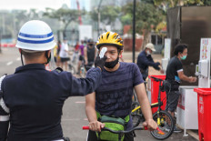 A security officer checks a resident's temperature at the entrance to the Gelora Bung Karno sports complex in Jakarta, on June 6, 2020. A surging number of cases and deaths prompted the Jakarta administration to reimpose large-scale social restrictions (PSBB) in September and ordered people to stay home.