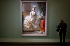 A visitor looks at a painting representing French queen Marie-Antoinette entitled 'Marie-Antoinette en grand habit' ('Marie-Antoinette in court dress', 1779-1788) by Elisabeth Vigee Le Brun displayed at 'Marie-Antoinette, Metamorphoses of an image' exhibition at the Conciergerie Paris museum, on October 15, 2019, on the eve of the first day of the exhibition opening. 