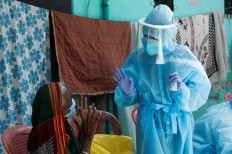 A healthcare worker wearing personal protective equipment (PPE) speaks to a resident about the coronavirus disease (COVID-19) at a check up camp in Dharavi, one of Asia's largest slums, Mumbai, India, June 7, 2020. 