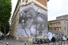 A man walks by a giant mural by French street artist JR paying tribute to Adama Traore, a black manwho died in police custody in 2016, on June 9, 2020 in Paris.