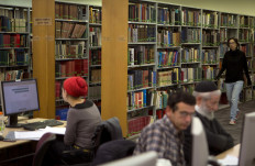 A woman walks past bookshelves at the National Library of Israel on the Givat Ram campus of the Hebrew University in Jerusalem on January 3, 2013.