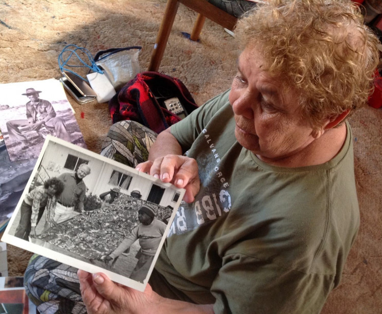 Batik nostalgia: Artist Barbara Weir in Alice Springs holds up a photo of her younger self and a long batik cloth. 