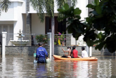 People ride a kayak around the Pantai Mutiara housing complex in North Jakarta on June 7 after a flood hit the area. The flooding began on Friday after a levee was breached, allowing sea water to inundate the area. JP/Wendra Ajistyatama