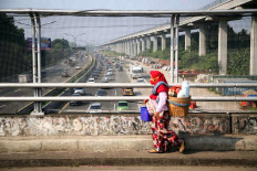 A jamu (herbal medicine) seller crosses a bridge above the Jagorawi toll road in Cibubur, East Jakarta, on Monday. JP/P.J. Leo
