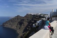 A woman gazes across the view of the town of Fyra in the island of Santorini on June 14, 2020 as the country prepares for the return of tourists to Greece from around 30 countries by air, sea and land. 