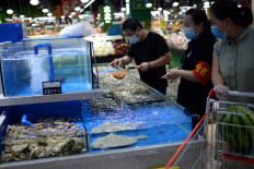 Customers wearing face masks shop live seafood at a Carrefour supermarket, following new cases of coronavirus disease (COVID-19) infections in Beijing, China June 17, 2020. 