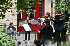 Residents listen to a so-called 'Hofkonzert' (backyard concert) by members of the Staatskapelle Berlin orchestra in Berlin on June 9, 2020.