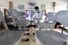 A school janitor lines up chairs and tables as he cleans an empty classroom at Bendungan Hilir 05 Pagi state elementary school in Central Jakarta, on June 22, 2020.