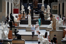 Visitors, wearing protective face masks, look at artworks during a visit at the Musee d'Orsay, the former Gare d'Orsay train station, in Paris as the museum re-opens doors to the public following the coronavirus disease (COVID-19) outbreak in France, on June 23, 2020. 