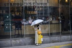 A woman wearing a facemask amid concerns over the spread of the COVID-19 coronavirus stands outside an opened Starbucks cafe in the Shibuya district of Tokyo on May 26, 2020, a day after the Japanese government lifted a nationwide state of emergency. 