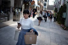 A woman looks at her phone while walking on a street in Tokyo on May 21, 2018.
