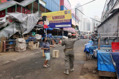 A Public Order Agency (Satpol PP) officer puts up a banner reminding residents that wearing masks in public is mandatory, at Kebayoran Lama Market in South Jakarta on June 19. The market was closed from June 18 to 20 after vendors tested positive for COVID-19. JP/Dhoni Setiawan
