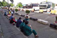 Intercity bus drivers and workers eat snacks while waiting for passengers at Kampung Rambutan terminal on Thursday. Bus service to West Java and Banten has resumed at the terminal. JP/P.J.Leo
