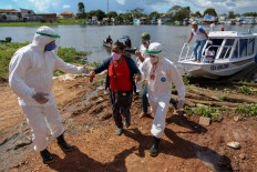Health professionals help patients with symptoms of the new coronavirus brought on a boat ambulance from Vila Amazonia community upon their arrival in Parintins, Amazonas state, Brazil, on June 27, 2020. 