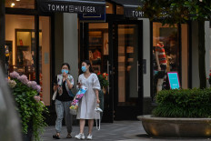 People wearing face masks walk in a shopping mall in Shanghai on June 16, 2020. 