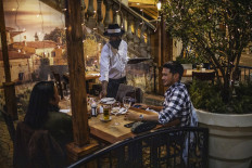 A waiter serves people having dinner in a restaurant at the Montecasino complex in Johannesburg, on July 3, 2020. 