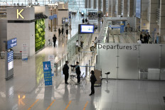 A member of the South Korean military support team (bottom C) checks the body temperature of a passenger at a gate in the departure hall at Incheon international airport, west of Seoul, on March 17, 2020. 