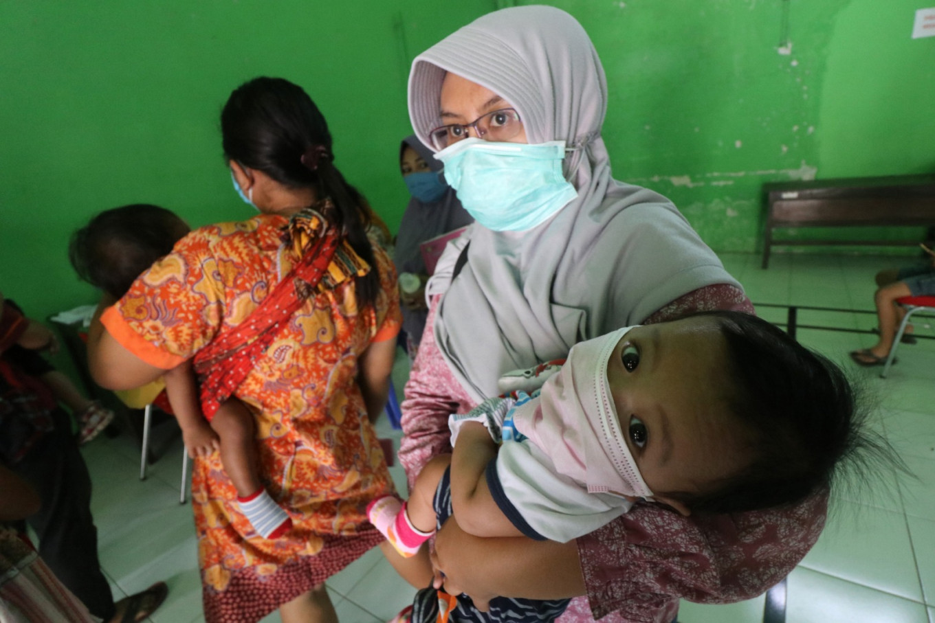 Safety first: Mothers stand in line to get their toddlers vaccinated at a village administration office in Kediri, East Java. The office is
being used for immunizations to prevent crowding at the local community health center (Puskesmas) and stem COVID-19 transmissions.