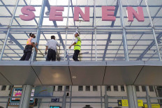 Workers clean the windows of Senen Station in Central Jakarta on June 29. State-owned train operator PT Kereta Api Indonesia (KAI) has resumed operations of several long-distance train services under strict health protocols. JP/P.J.Leo