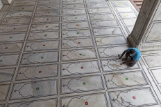 A worker places a sticker on the floor for devotees to maintain social distancing during prayers as the Jama Masjid mosque reopens after the government eased a nationwide lockdown imposed as a preventive measure against the spread of the COVID-19 coronavirus, in the old quarters of New Delhi on July 7, 2020. - India on July 6 became the country with the third-highest coronavirus caseload in the world, as a group of scientists said there was now overwhelming evidence that the disease can be airborne -- and for far longer than originally thought. India's major cities including New Delhi and Mumbai are suffering the most, and critics say not enough tests are being conducted -- meaning that many COVID-19 infections are likely to go undiagnosed. 