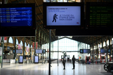 Security staff stand in background of a screen displaying instructions concerning novel coronavirus spread at Gare du Nord in Paris on April 1, 2020, on the sixteenth day of a lockdown in France aimed at curbing the spread of the COVID-19 (novel coronavirus).
