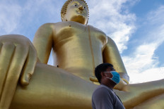 In this photo taken on July 2, 2020, a visitor walks past the largest Buddha statue in Thailand, in Ang Thong province, north of Bangkok, as authorities reopened sites to tourists following lockdowns to halt the spread of the COVID-19 novel coronavirus.

