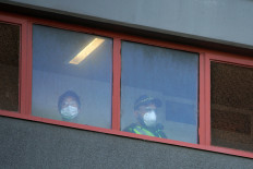 Police officers look out the windows of a public housing tower, locked down in response to an outbreak of the coronavirus disease (COVID-19), in Melbourne, Australia, July 8, 2020.   (REUTERS/Sandra Sanders).
Usage: 0