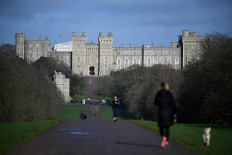 A woman walks with a dog along the Long Walk at Windsor Castle in Windsor, west of London on January 9, 2020. 