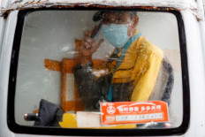A delivery driver speaks on the phone as he sits in the cabin of his electric delivery vehicle on a rainy day following an outbreak of the COVID-19 in Beijing, China, on Thursday. 
