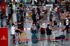Passengers wearing masks for protection against the COVID-19 queue at the check-in counters of Emirates airline, in Ninoy Aquino International Airport in Pasay City, Metro Manila, Philippines, July 9, 2020.Emirates, the largest airline in the Middle East, will cover customers' coronavirus-related medical costs in a bid to "boost travel confidence", the Dubai Media Office said Thursday.