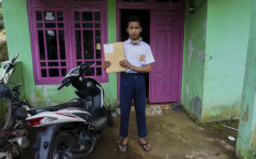 SMP 4 Bawang student Khoerul Risal poses in front of his house in Batang regency, Central Java with his weekly assignments he just received from his teacher. Antara/Harviyan Perdana Putra