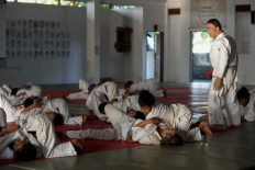 This photo taken on Feb. 4, 2020 shows Japanese judo master Tsuneo Sengoku (right) watching as his students train at the Sengoku International Judo Hall in Gianyar on Indonesia's Bali island. - The 75-year-old 