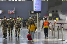 An airport staff (R) sprays disinfectant while Central Industrial Security Force (CISF) personnel patrol the domestic departure check-in terminal of Bangalore International Airport in Bangalore, on June 2, 2020.
