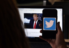In this photo illustration, a Twitter logo is displayed on a mobile phone with President Trump's Twitter page shown in the background on May 27, 2020, in Arlington, Virginia. 