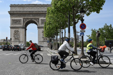People ride on their bicycles in The Champs Elysees Avenue , in Paris, on May 11, 2020, on the first day of France's easing of lockdown measures in place for 55 days to curb the spread of the COVID-19 pandemic, caused by the novel coronavirus. 