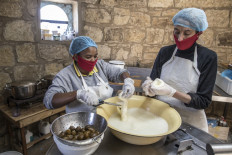 Assistant cheesemaker Jeanet Mapula Mokwena (left) prepares fig filled scamorza cheese at the dairy of South African cheesemaker Marietjie Crowther (right) in Clarens, on July 13, 2020 in the small lab-turned-hut of Noah's Cheese, the small artisanal dairy she runs with her husband Danie. 