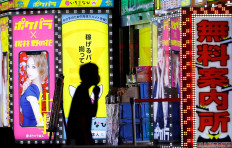A man wearing a face mask walks past a signboard of a bar in the Kabukicho district, amid the coronavirus disease (COVID-19) outbreak in Tokyo, Japan, on July 14, 2020. 