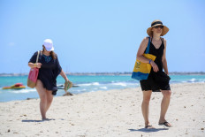 European tourists walk at the beach at a hotel on the Tunisian island of Djerba on July 18, 2020, a day after the arrival of the first charter flights to the country since the COVID-19 crisis erupted. 