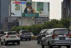 Motorists ride past giant electronic billboards promoting the fight against the COVID-19 coronavirus pandemic in Jakarta on July 21. 