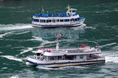 American tourist boat Maid Of The Mist, limited to 50 percent occupancy under New York state's rules amid the spread of the coronavirus disease (COVID-19), glides past a Canadian vessel limited under Ontario's rules to just six passengers, in Niagara Falls, Ontario, Canada, on July 21, 2020. 